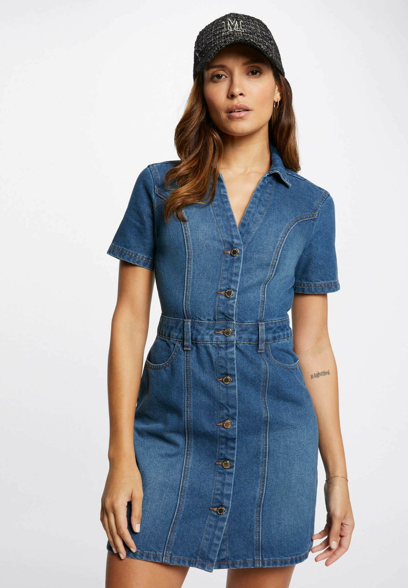 Robe en denim à manches courtes avec col boutonné, taille cintrée et poches avant. Couleur bleu clair avec détails de couture contrastants.
