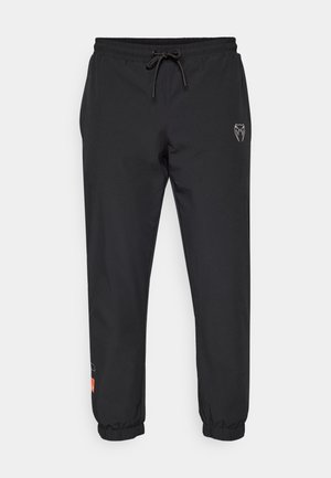Black jogger pants made of lightweight material, featuring an elastic waistband with drawstring, tapered legs, and logo accents on the front.