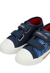 Paire de baskets pour enfants bleu marine avec embouts en caoutchouc blanc, logo Spider-Man sur les sangles, et motif toile d’araignée bleu sur une chaussure.