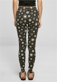 Leggings neri con un motivo di soli e lune in tonalità crema e gialla. Design aderente, tessuto elasticizzato, lungo fino alla caviglia con vita alta.