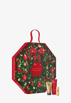 Calendrier de l'Avent octogonal rouge décoré de sapin, d'ornements et d'un nœud. Comprend des portes numérotées et inclut trois produits cosmétiques à la base.