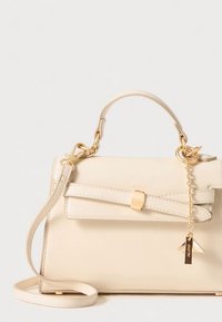 Beige leather handbag with a structured design, bow accent, gold-tone hardware, detachable shoulder strap, and a branded charm.