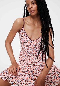 Roosa lillemustriga kleit, millel on V-kaelus, õhukesed spagettrihmad ja lehvikseelik. Kaunistatud lillaka äärega.