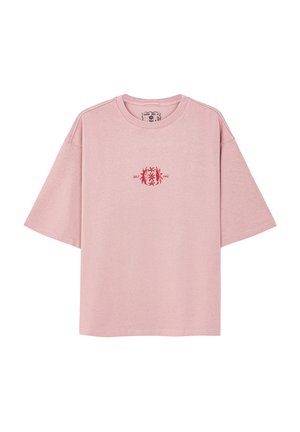 Różowa bawełniana koszulka z luźnym krojem, krótkimi rękawami, okrągłym dekoltem i małym czerwonym wzorem na piersi.