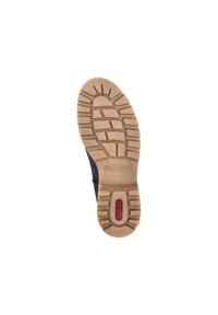 La semelle de la chaussure présente un motif de grip en caoutchouc brun avec des rainures profondes et un petit logo rouge. Le matériau semble durable et texturé.