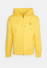 Gul zip-up hoodie i mjukt tyg, med en kenguruficka, dra på huva och liten svart logotyp på bröstet.