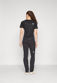 Black athletic shirt and pants, featuring a logo on the upper back and thigh, made from smooth material with a fitted design.