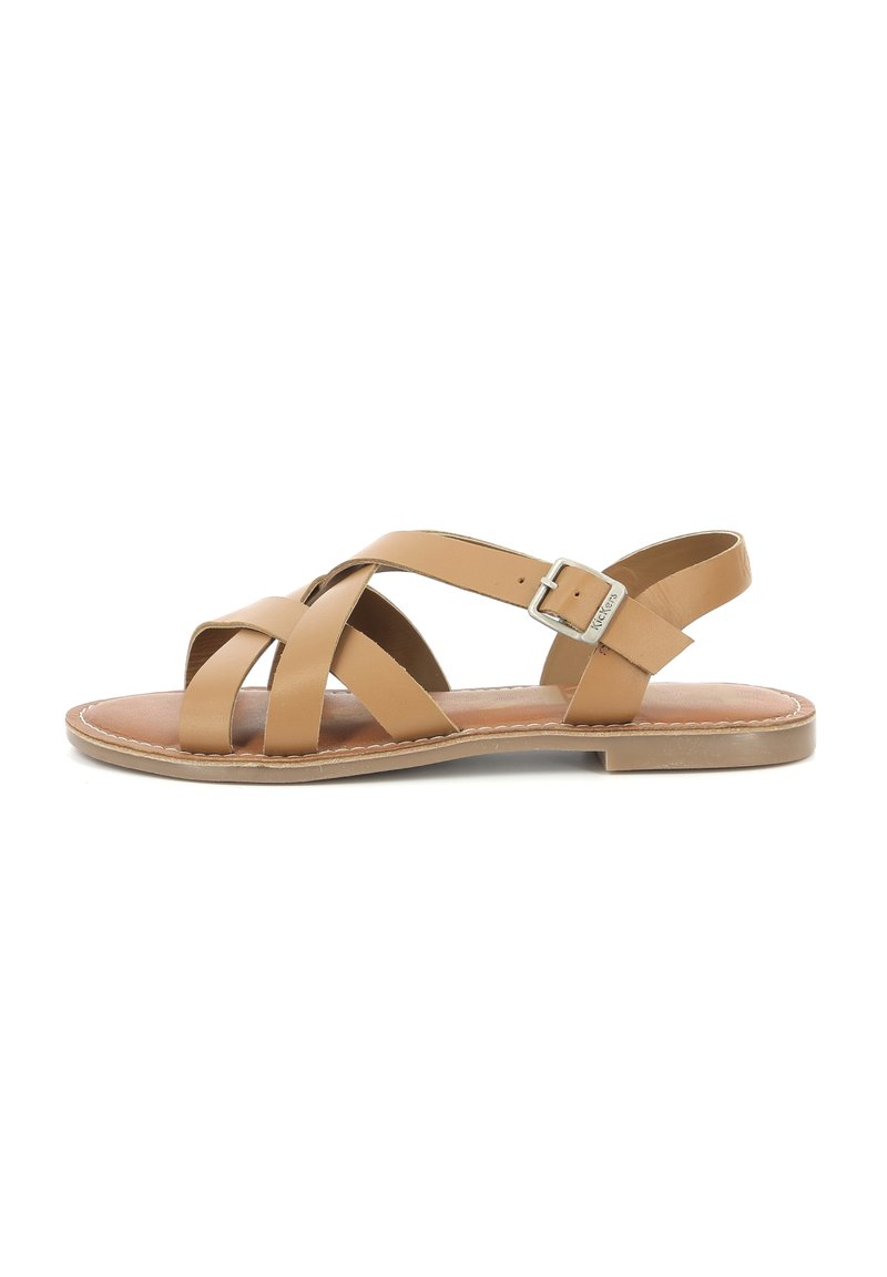 Tan leren sandaal met kruiss straps, een gespsluiting bij de enkel, platte zool en een bruine binnenzool, met een eenvoudig ontwerp en subtiele stiksels.