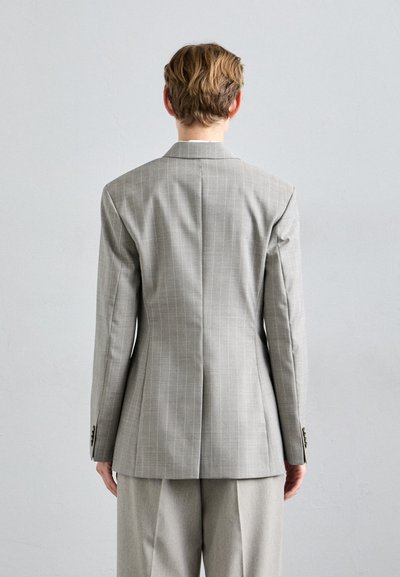 Gray pinstriped blazer with structured shoulders, single vent, and tailored fit. Material appears smooth with subtle sheen; paired with matching trousers.