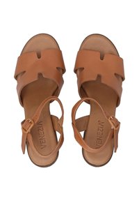 Tan leren sandalen met uitsnijdingen. Voorzien van een enkelbandje met een gesp en een comfortabele inlegzool. Platte zool voor extra comfort.