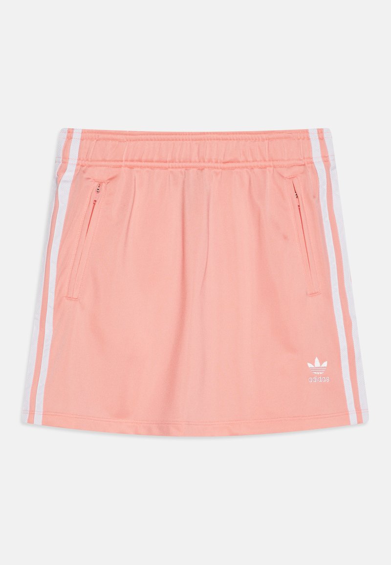 Falda deportiva color durazno con cinturilla elástica, rayas laterales blancas y bolsillos con cremallera. Presenta el logo de Adidas en blanco en la parte inferior izquierda.