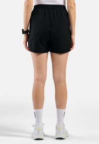 Zwarte sportshorts met een elastische tailleband, boven de knie lengte, gecombineerd met witte sokken en sneakers. Minimalistisch ontwerp, gladde textuur.