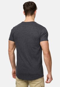 Mørkegrå tætsiddende T-shirt med korte �ærmer, rund hals og en let længere bagkirtel. Blødt, struktureret stof med et sømløst design.
