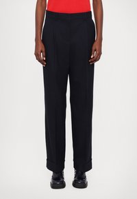 Pantaloni sartoriali blu scuro con davanti piatto, pieghe e fondo con risvolto. Realizzati in un tessuto liscio, presentano passanti per cintura e tasche laterali.