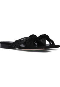 Zwarte platte sandalen met een geknoopt ontwerp, gemaakt van textuur materiaal. De zool is laagprofiel en glad, met een lichte glans.
