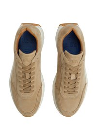 Zapatillas de ante beige con un acabado texturizado, que presentan cordones a juego, una suela blanca y una suela exterior de goma marrón. Logo grabado en el interior.