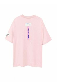 Camiseta de algodón rosa con mangas cortas, un corte relajado y un diseño impreso que presenta etiquetas y gráficos en la parte trasera y las mangas.