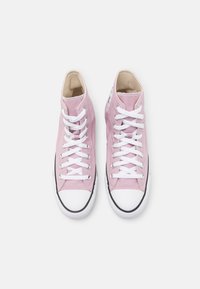 Zapatillas altas de lona rosa con cordones blancos, puntera de goma blanca y detalles de suela negra. Presenta un parche de logo en el costado.