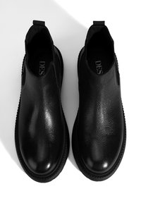 Bottes noires en cuir avec une finition texturée, panneaux latéraux élastiques et bout arrondi, dotées d'une semelle en caoutchouc avec un motif de traction.