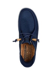 Zapato sin cordones azul marino con parte superior de tela texturizada, plantilla de corcho y cordones elásticos; suela de goma y sutiles acentos de costura.