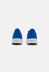 Baskets de sport bleues avec un dessus texturé et des accents noirs contrastants. La semelle est blanche avec un motif noir pour l'adhérence.