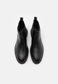 Černé kožené kotníkové boty s kulatou špičkou, elastickými bočními panely a poutky pro snadné obouvání. Hladký povrch a šité detaily podél podrážky.