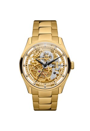 Kultainen metallirannekello, jonka läpinäkyvä kellotaulu paljastaa sisäiset rattaat. Mustat tunti-, minuutti- ja sekuntiviisarit osoittavat aikaa 10:10:37.