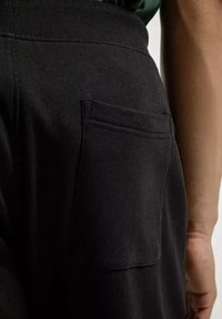 Czarne dresy z prążkowanym pasem w talii i tylną kieszenią naszywaną, wykonane z miękkiego materiału o gładkiej fakturze.