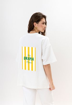 Witte oversized t-shirt met een kleurrijke graphic op de achterkant, met gele en witte strepen en de tekst "Geen DRAMA AUB."