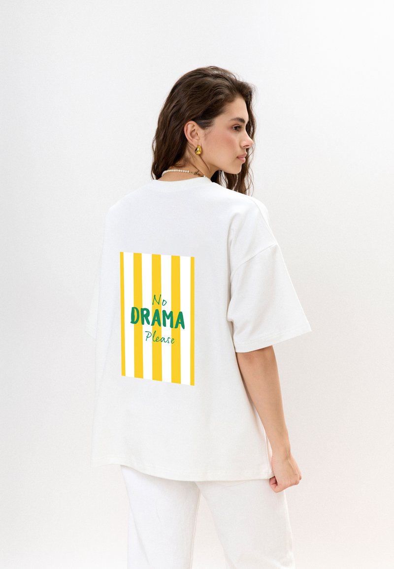Witte oversized t-shirt met een kleurrijke graphic op de achterkant, met gele en witte strepen en de tekst "Geen DRAMA AUB."