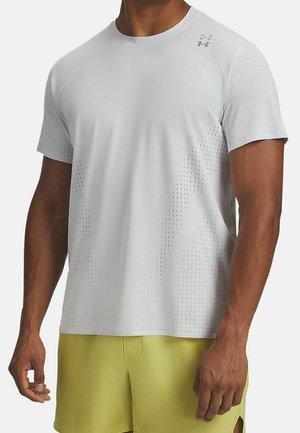 Uomo che indossa una maglietta sportiva a maniche corte traforata grigio chiaro e pantaloncini gialli, in piedi con le braccia rilassate ai lati.