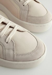 Helle rosa Sneaker aus einer Mischung aus glattem Leder und weichem Wildleder, mit runden Schnürösen und einer strukturierten Gummisohle.