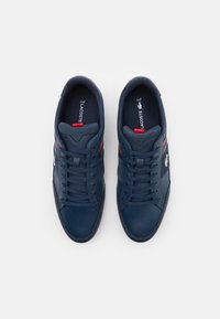 Baskets bleu marine en mesh et cuir synthétique avec une finition texturée, présentant des accents rouges et un design à lacets.