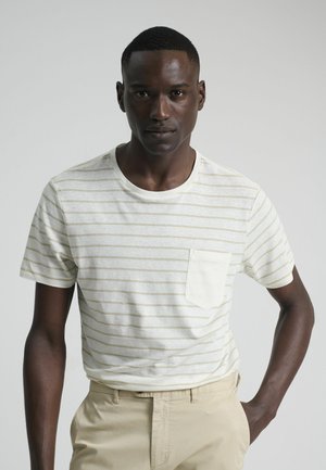 Camiseta blanca de manga corta con rayas horizontales en color crema y un bolsillo en el pecho, combinada con pantalones beige claros. Textura de tela suave.