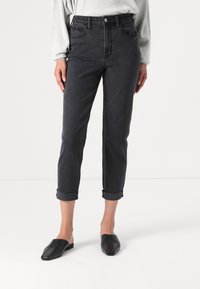 Jeans neri a vita alta con orli arrotolati, caratterizzati da una morbida texture in denim e un classico design a cinque tasche. Abbinati a mule neri piatti.