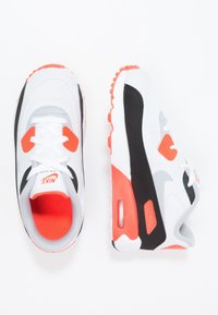 Nike Air Max sneakers i vitt, svart och orange. Mesh-överdel med fasta accenter, vadderad sula och synlig luftkudde i hälen. Klassisk design.