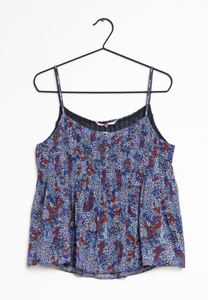 Blouse sans manches à fleurs bleues avec fines bretelles noires suspendue à un cintre en fil noir sur fond blanc.