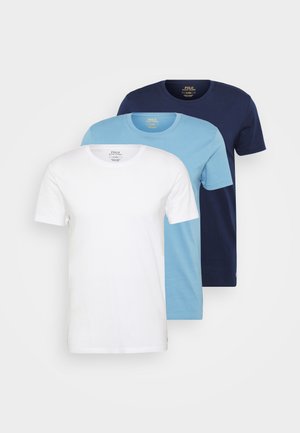 Trois t-shirts à col rond : un blanc, un bleu clair et un marine. Chacun a des manches courtes et une texture lisse, avec une étiquette sur le col.