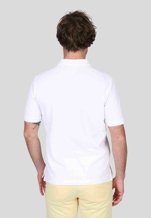 Polo shirt blanc à manches courtes vu de l'arrière, présentant un col classique et des fentes sur les côtés, fabriqué en tissu de coton lisse.