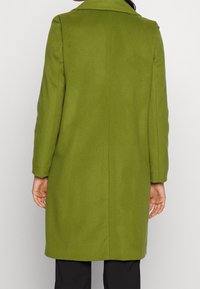 Grüner Wollmantel mit klassischem Kragen, langen Ärmeln und geradem Schnitt. Verfügt über eine glatte Textur und eine minimalistische Gestaltung.