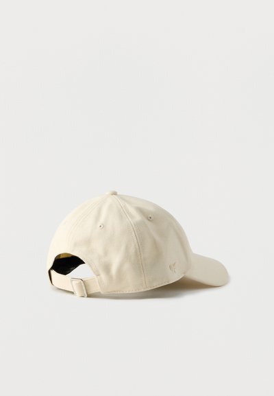 Καφέ καπέλο του μπέιζμπολ με καμπύλη γείσο, υφασμάτινη υφή, ρυθμιζόμενο πίσω λουράκι και μικρή λεπτομέρεια με λογότυπο πάνω από το κούμπωμα.