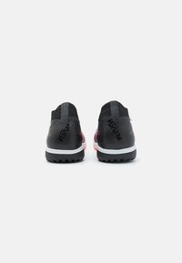Chaussures de sport noires avec une tige en mesh, présentant un dégradé violet, une semelle intermédiaire blanche et une semelle extérieure en caoutchouc texturé.