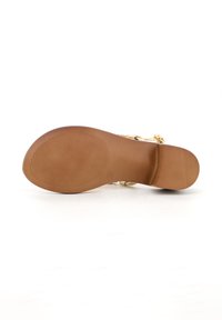 Sola in gomma marrone con righe orizzontali, caratterizzata da una cintura dorata e hardware decorativo. Texture liscia e dettagli minimi.