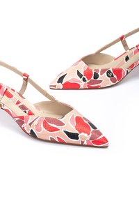 Zapatos slingback de punta afilada con un patrón floral en rojo, rosa y negro sobre un fondo texturizado beige; cuentan con una correa delgada y un tacón bajo.