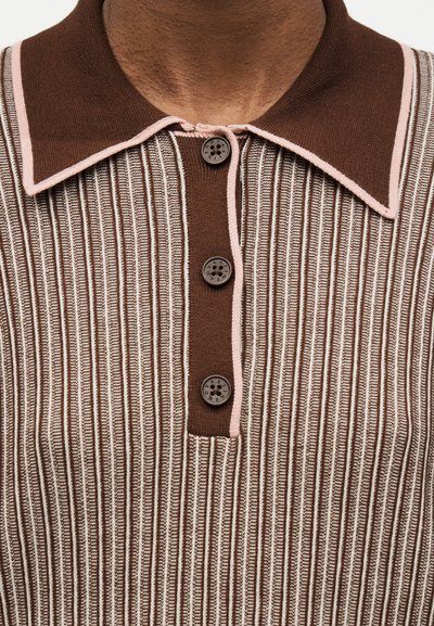 Κοντινό πλάνο ριγέ πλεκτού πουκάμισου σε καφέ και λευκό με σκούρο καφέ γιακά και τρία σκούρα καφέ κουμπιά στην πατιλέτα.