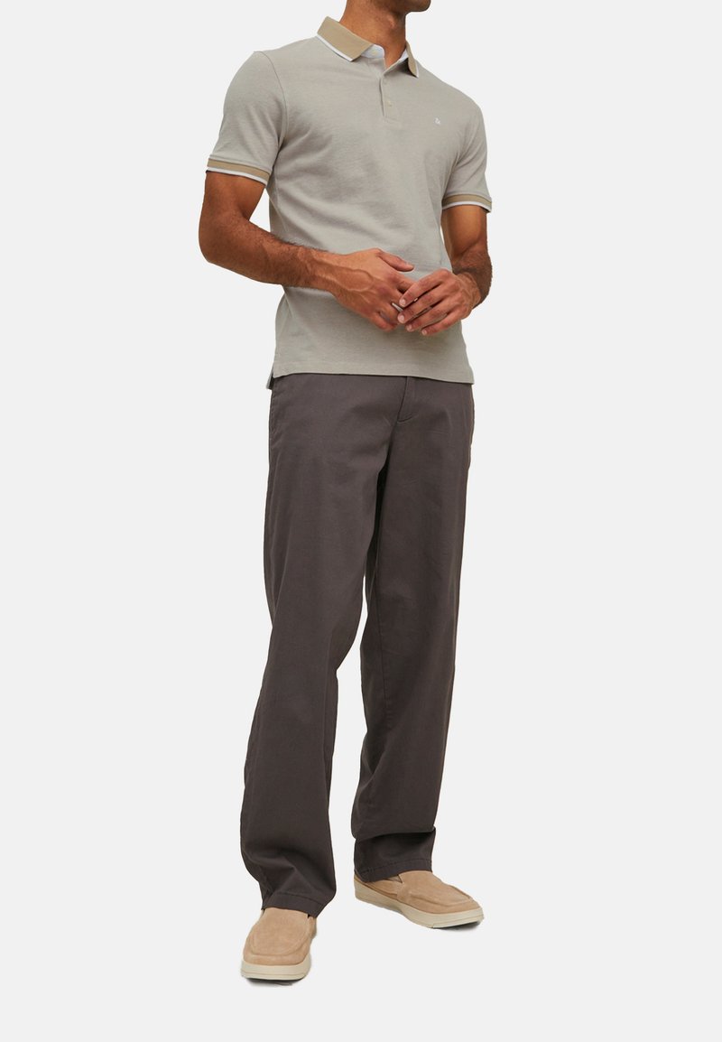 Lys grå polo skjorte med en beige krave og ærme accenter, kombineret med løstsiddende mørkegrå bukser og beige slip-on sko.