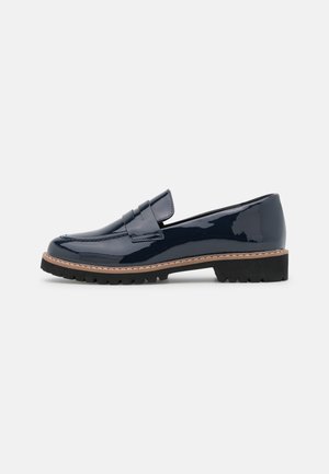 Mocassin à enfiler en cuir verni bleu marine avec semelle noire épaisse et surpiqûres beige, style sans lacets avec une bride sur le dessus.