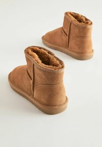 Bruna mockaskinnanklar med mjukt foder av päls, rund tå och gummisula; har en något texturerad ovandel och synliga sömdetails.