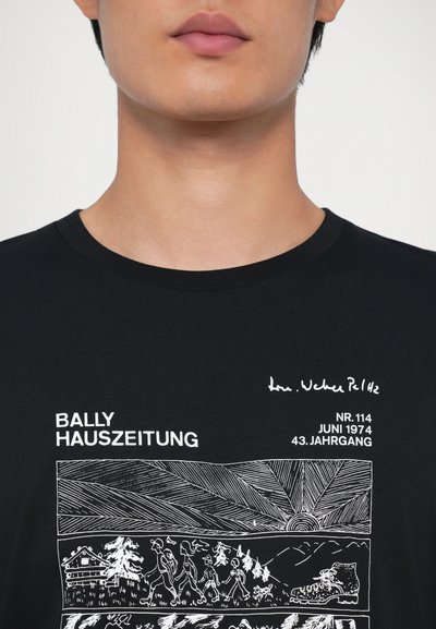 Melnas kokvilnas T-krekls ar baltajiem drukātiem grafikiem, tostarp tekstu "BALLY HAUSZEITUNG" un detalizētu cilvēku un ainavu ilustrāciju.