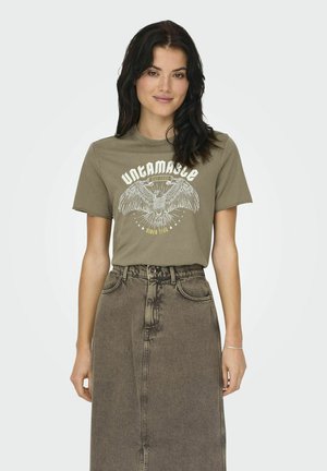 Camiseta de algodón verde oliva con un gráfico de un águila blanca y el texto "UNTAMABLE", combinada con una falda de mezclilla descolorida de cintura alta.